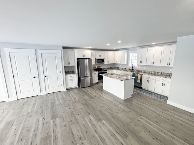 kitchen featuring appliances with stainless steel finishes, a center island, sink, and white cabinets