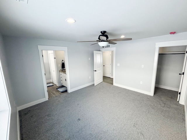 unfurnished bedroom with connected bathroom, carpet floors, a walk in closet, ceiling fan, and a closet