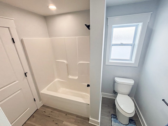 bathroom featuring wood-type flooring, bathing tub / shower combination, and toilet