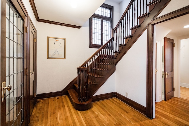 stairs with crown molding and wood-type flooring