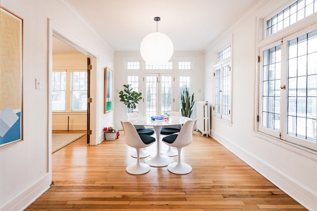 dining area featuring radiator, ornamental molding, and light wood-type flooring