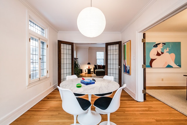 dining space featuring french doors, ornamental molding, and light wood-type flooring