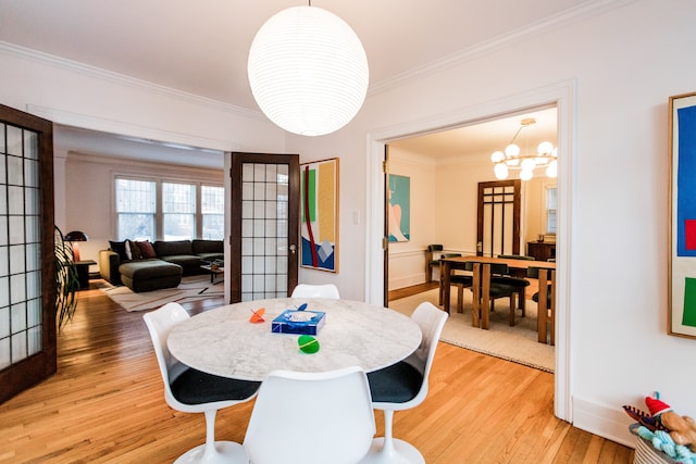 dining area featuring crown molding, an inviting chandelier, and light hardwood / wood-style floors