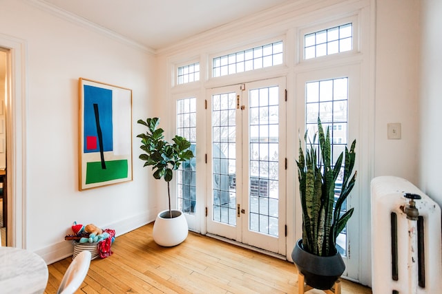 doorway with crown molding, french doors, and light wood-type flooring