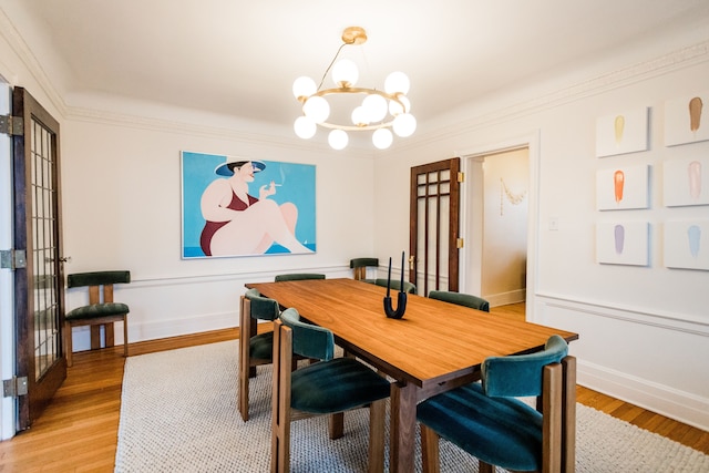 dining area with hardwood / wood-style floors, ornamental molding, and a chandelier