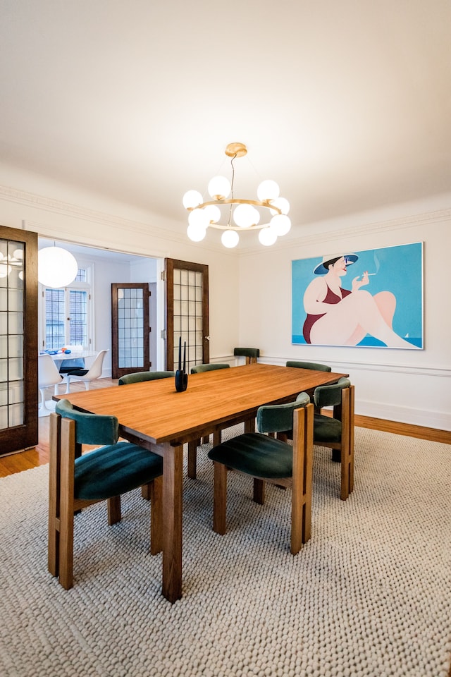 dining area featuring wood-type flooring, ornamental molding, and a chandelier