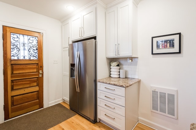 kitchen featuring white cabinetry, backsplash, stainless steel refrigerator with ice dispenser, light stone counters, and light wood-type flooring