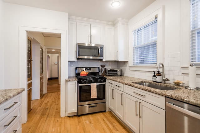 kitchen featuring white cabinetry, appliances with stainless steel finishes, sink, and light stone counters