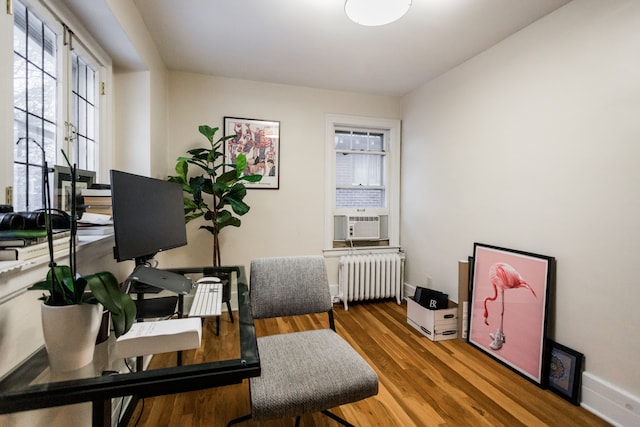 office space featuring cooling unit, wood-type flooring, and radiator