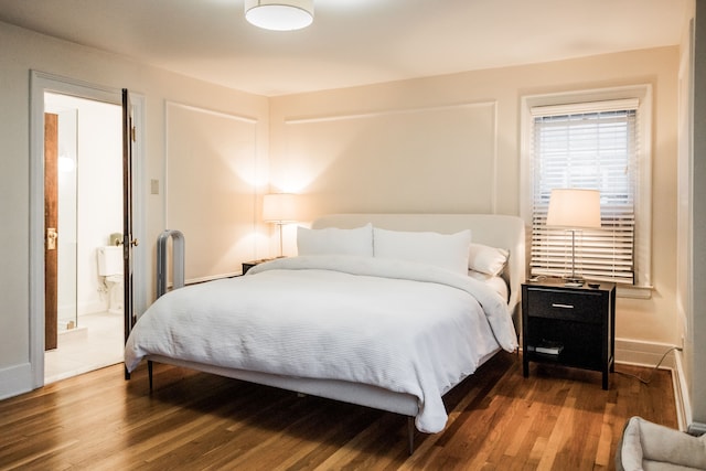 bedroom with connected bathroom and hardwood / wood-style flooring