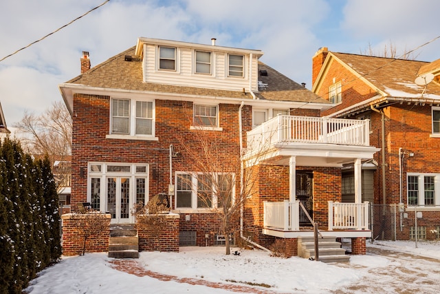 snow covered rear of property featuring french doors and a balcony