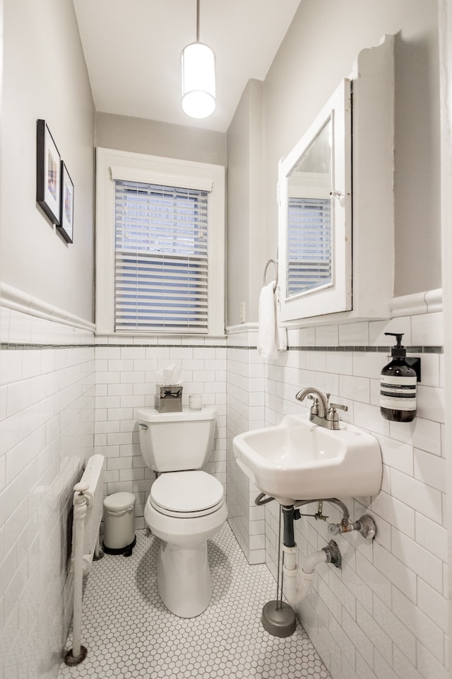 bathroom featuring tile patterned floors, toilet, sink, tile walls, and radiator heating unit