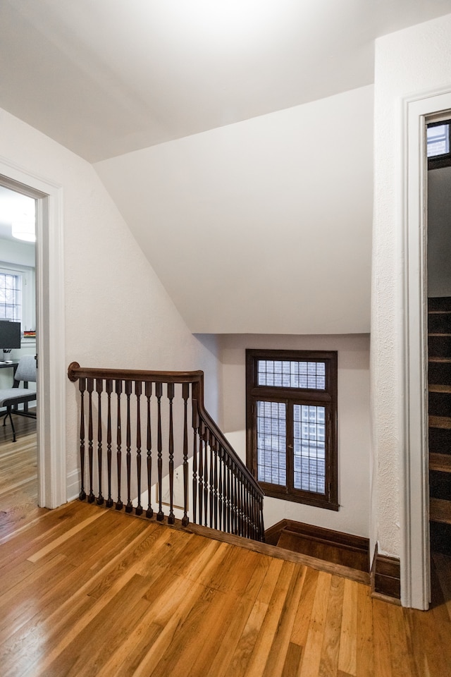 staircase with hardwood / wood-style floors and vaulted ceiling