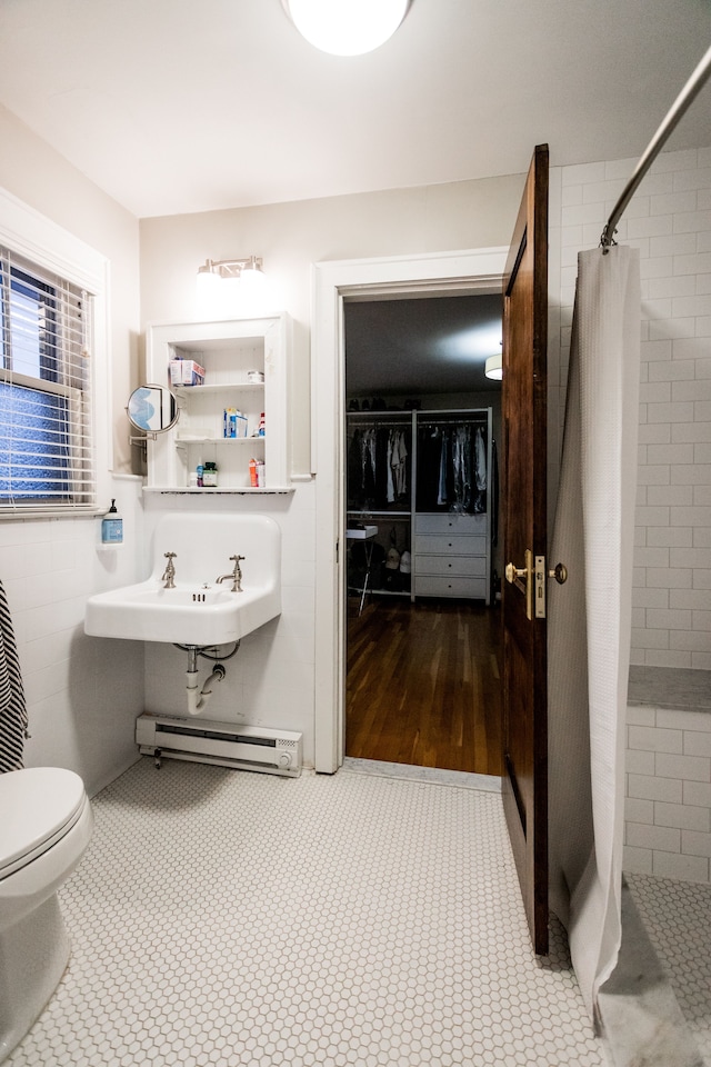 bathroom with toilet, sink, tile walls, a baseboard radiator, and a shower with shower curtain