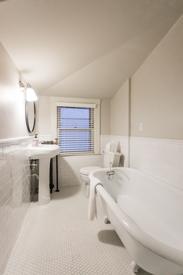 bathroom featuring lofted ceiling, tile patterned floors, tile walls, and toilet