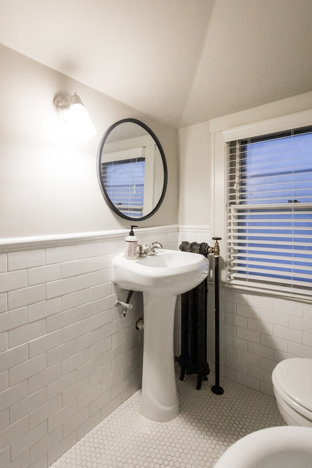 bathroom featuring tile patterned flooring, vaulted ceiling, tile walls, and toilet