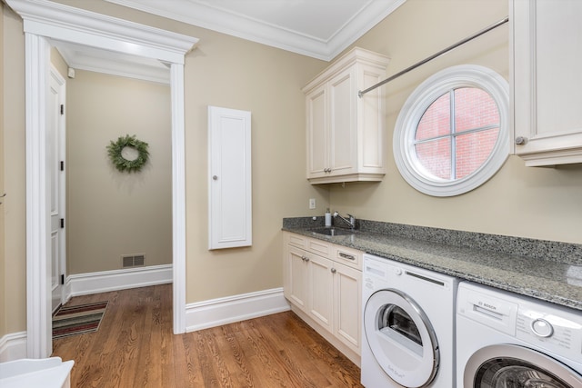 washroom featuring separate washer and dryer, sink, dark hardwood / wood-style flooring, cabinets, and crown molding