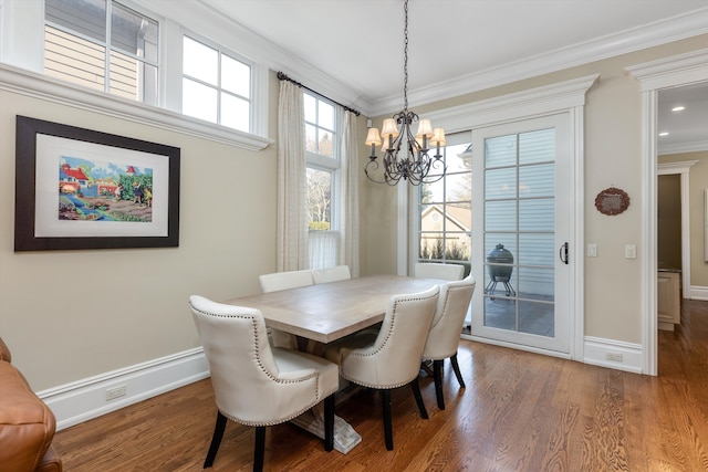 dining space with hardwood / wood-style flooring, ornamental molding, an inviting chandelier, and a baseboard radiator