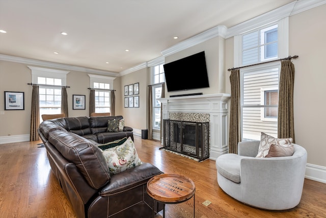 living room with crown molding, a tile fireplace, and light wood-type flooring