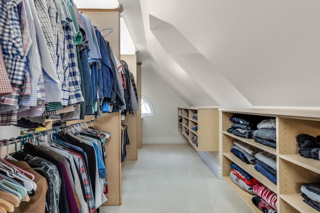 walk in closet with light colored carpet and lofted ceiling