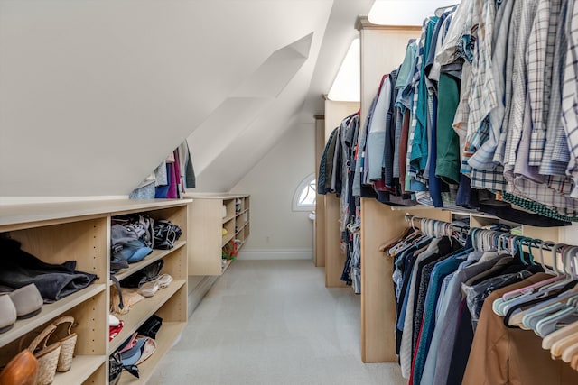 spacious closet featuring light colored carpet and lofted ceiling