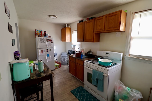 kitchen featuring white appliances, light hardwood / wood-style flooring, and a textured ceiling