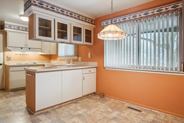 kitchen featuring sink, white cabinetry, hanging light fixtures, white cooktop, and kitchen peninsula