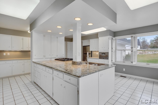 kitchen with white cabinetry, sink, a kitchen island, and light tile patterned floors