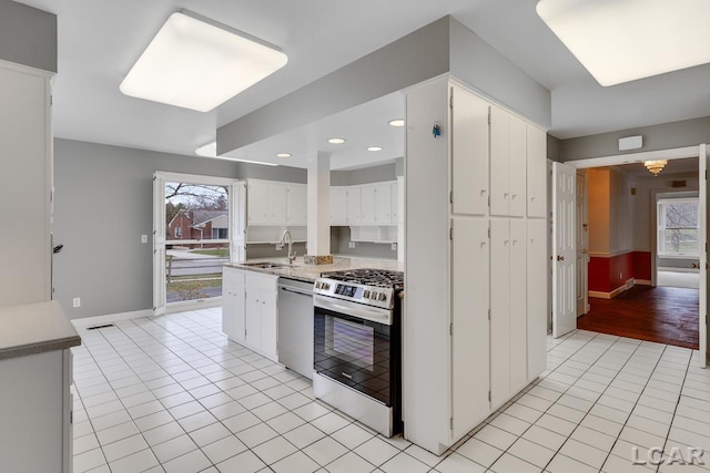 kitchen with stainless steel appliances, sink, light tile patterned floors, and white cabinets