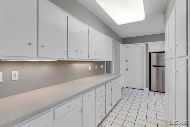 kitchen featuring white cabinetry, light tile patterned floors, and stainless steel refrigerator