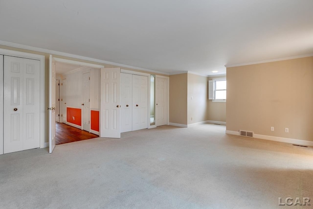 interior space featuring two closets, ornamental molding, and carpet flooring