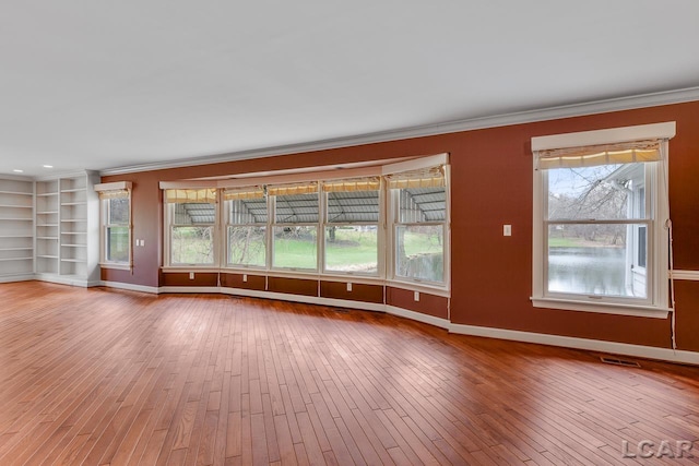 unfurnished living room featuring ornamental molding and light wood-type flooring