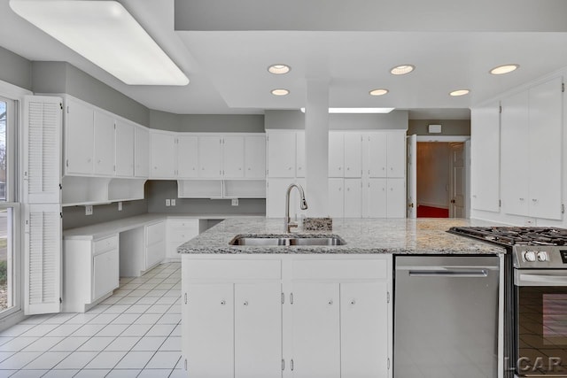 kitchen with white cabinetry, stainless steel appliances, light stone countertops, and sink