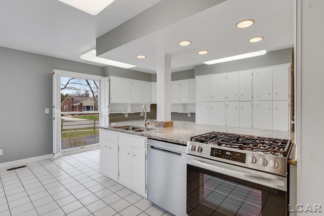 kitchen featuring sink, light tile patterned floors, white cabinetry, stainless steel appliances, and light stone countertops