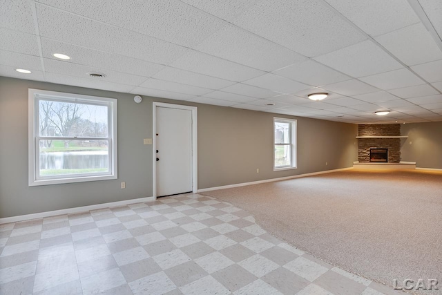 unfurnished living room featuring a stone fireplace and a drop ceiling