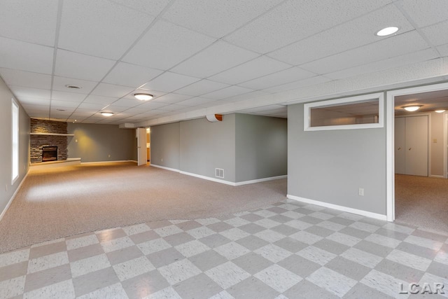 basement with light carpet, a fireplace, and a paneled ceiling