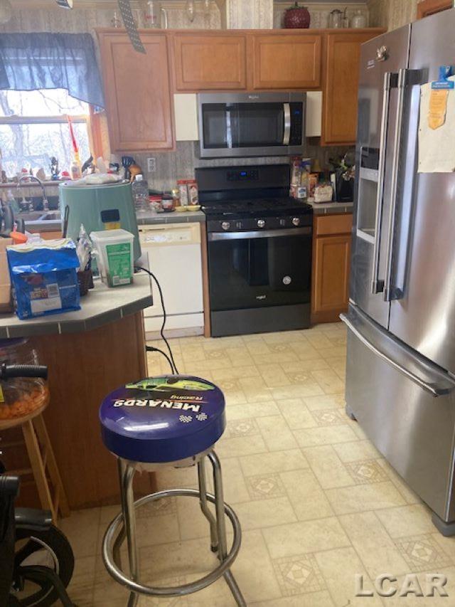 kitchen with stainless steel appliances, tile counters, and backsplash