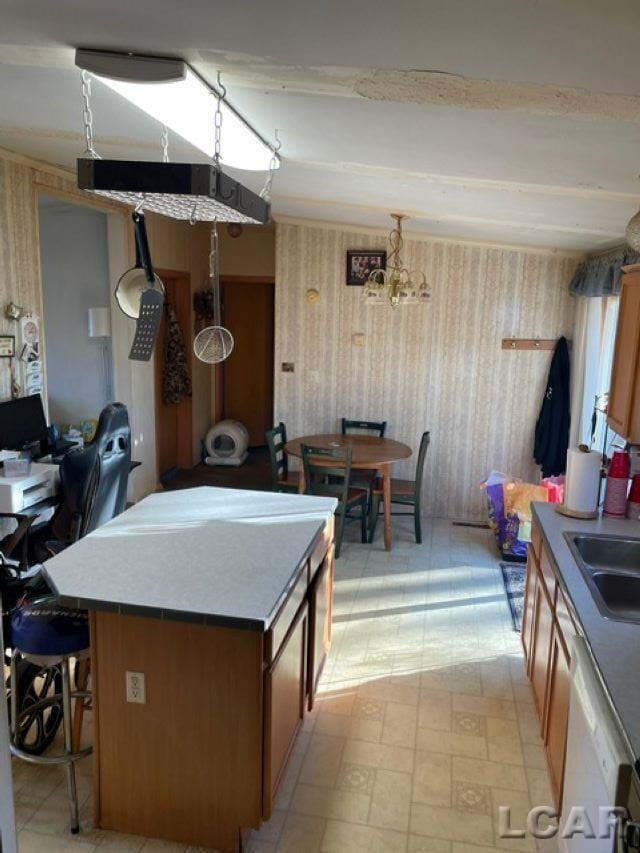 kitchen featuring sink, dishwasher, hanging light fixtures, a center island, and beamed ceiling