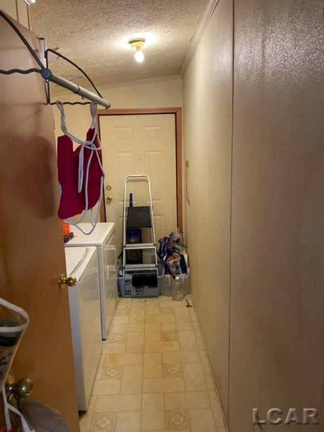 clothes washing area with ornamental molding, a textured ceiling, and washer and clothes dryer