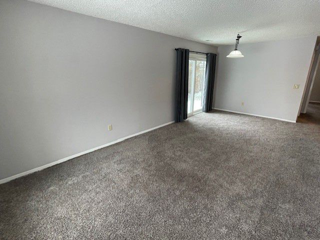 carpeted empty room featuring a textured ceiling