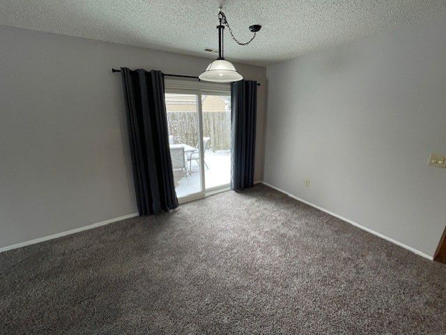 empty room with a textured ceiling and dark colored carpet