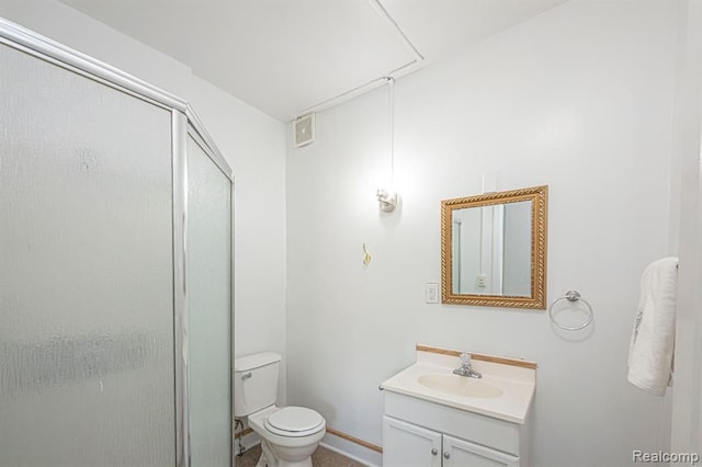 bathroom featuring vanity, a shower with door, and toilet