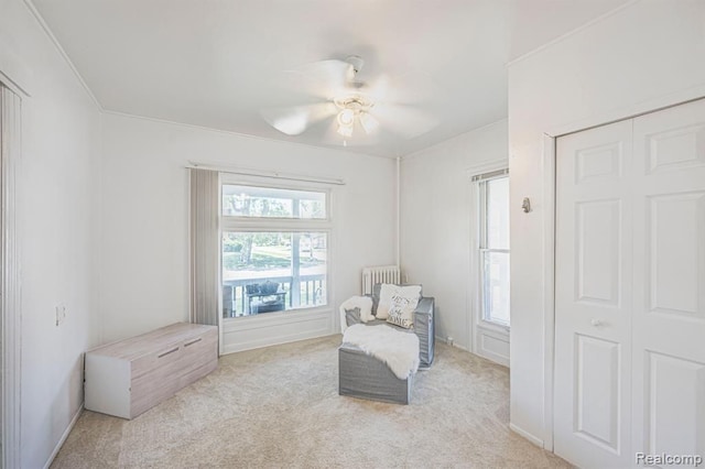 sitting room with a healthy amount of sunlight, radiator, light colored carpet, and crown molding