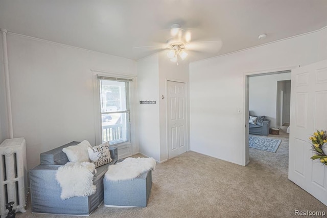 living area with ceiling fan, radiator heating unit, and light carpet