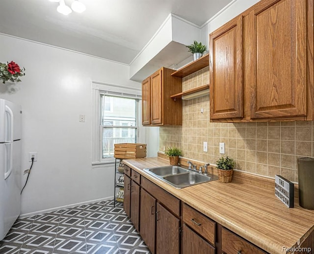 kitchen featuring tasteful backsplash, sink, crown molding, and white fridge