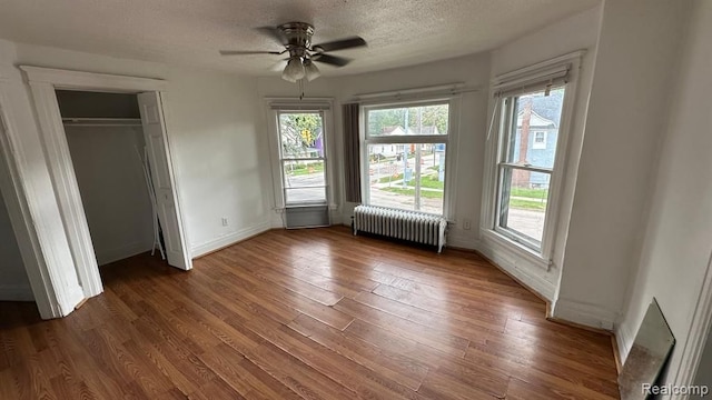 unfurnished bedroom featuring ceiling fan, radiator heating unit, a textured ceiling, and dark hardwood / wood-style flooring