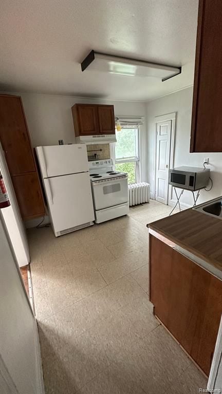 kitchen with white appliances and radiator heating unit