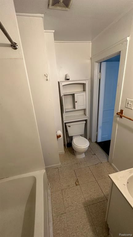 bathroom with vanity, a tub to relax in, and toilet