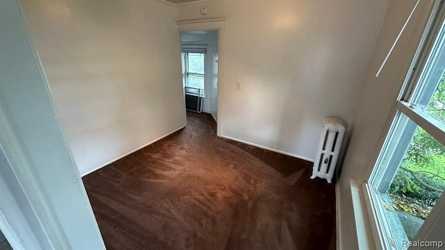 empty room featuring radiator and dark carpet