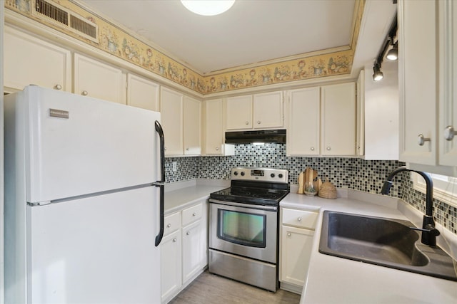 kitchen with sink, decorative backsplash, stainless steel range with electric stovetop, white fridge, and light wood-type flooring